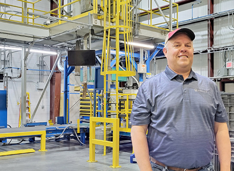Beck’s plant manager Ryan Petr stands in front of a seed corn bagging/boxing machine in the huge processing facility near Phillips. Though empty now, the plant will begin to fill up with locally harvested seed corn starting in September. 