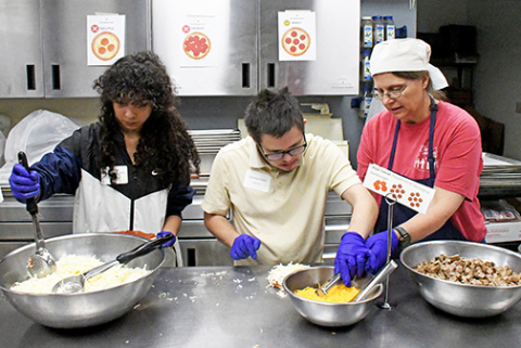 A student takes his turn at dressing one of the 130 personal pan pizzas that were served for lunch at The Leadership Center’s VLS Summit held on Thursday for 75 special needs students from across Nebraska. 