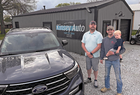 Rich Kinsey, left, poses with his son Kody Bengston and grandson Tatum on the new Kinsy Auto used car lot located along Highway 34 in Aurora.