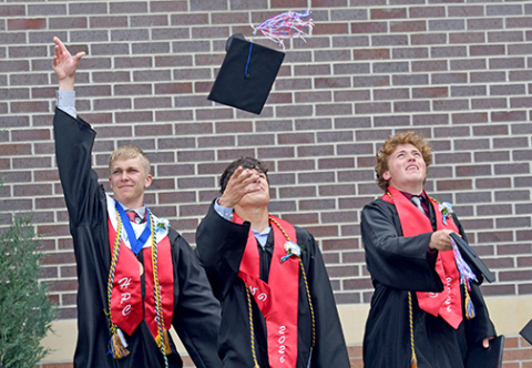 From left, HPC seniors Brodey Spurling, Levi Russell and Chase Owens toss their caps into the air after officially becoming Storm graduates Saturday afternoon. 