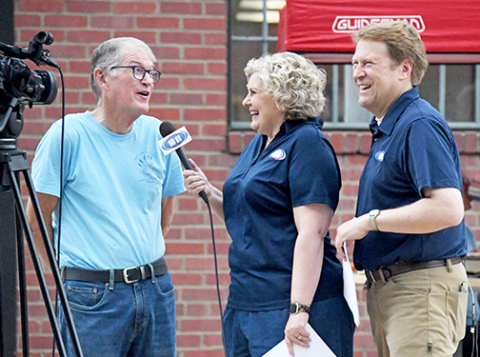 Channel 10/11 TV news anchors Taryn and Jon Vanderford (right) interview Hamilton County Food Pantry board member Bruce Ramsour during the annual Can Care-A-Van food drive last week.