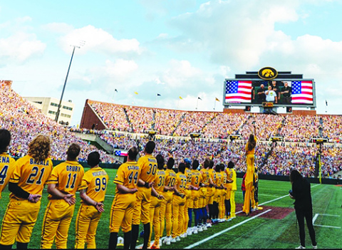 Aurora choir teacher Jason Frew, shown on the large scoreboard, performed the National Anthem during the Savannah Bananas baseball game at Kinnick Stadium in Iowa City July 4.