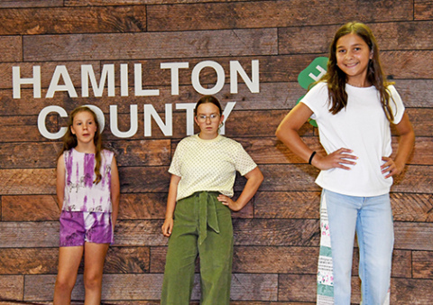 Eva De La Cruz (right) models her 4-H fashion show entry on Monday night. Waiting to showcase their clothes are, from left, Augie Hansen and Zoey Gimpel.
