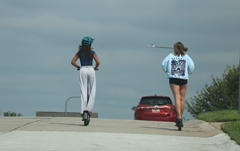 Two girls ride their e-scooters in a neighborhood off of 192nd and Harrison Streets in Omaha. Earlier this summer 11-year-old Logan Rahn died after a pickup truck collided with his electric scooter in Bennington.