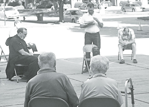 Pastor Bob Gannon (center) takes a moment to share a prayer with the residents for the community of Aurora. News-Register/Jeni Moellenberndt