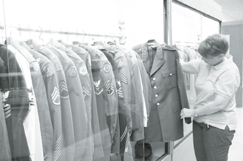 Plainsman Museum executive director Tina Larson is fond of the military jacket exhibit due to its wide array of years, patches and branches. She is seen here with Roger Luthy’s jacket. News-Register/Cheyenne Rowe