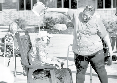 Staff and residents at Memorial Community Care in Aurora celebrated the anticipated opening of the long-term care facility to visitors Monday with a good old-fashioned water fight. Pictured above, Bud Pence gets doused by MCC activities director Jessie Morales. At left, Lois Jensen tosses a water balloon toward a staff member. The facility has been closed to visitors since mid-March due to the coronavirus pandemic.