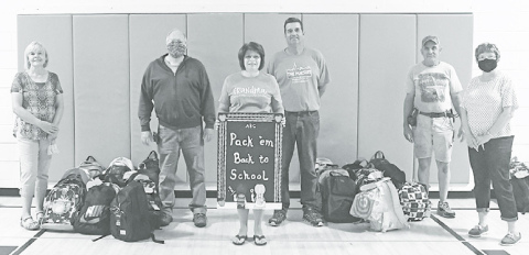 Marilyn Vrana (left), David Olson, Holly Schmit, Phil Troester, Bob Spotanski and Laura Jobman stand with a portion of the 93 donated backpacks for students at Aurora Elementary and Middle School. News-Register/Jeni Moellenberndt