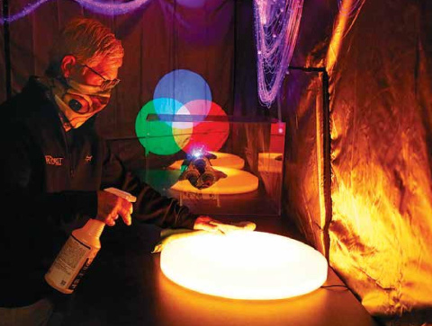Edgerton educator Deb Miller takes a minute when the Edgerton is without guests to sanitize objects inside the new ‘laser island’ exhibit. News-Register/Cheyenne Rowe