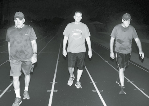 Pictured from left, Kelly Grossnicklaus, Jeff Bart and Todd Jensen walk on the AHS track Friday, the 20th anniversary of when the daily 3-mile routine began. News-Register/Kurt Johnson