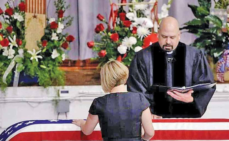 Dena Yllescas stands over her husband’s casket, Army Capt. Robert Yllescas, at his funeral in 2009. Yllescas died at the age of 31, after complications from a targeted attack by Afghan o auroranewsregister.com insurgents. This story is told in new film, “The Outpost.” Courtesy photo