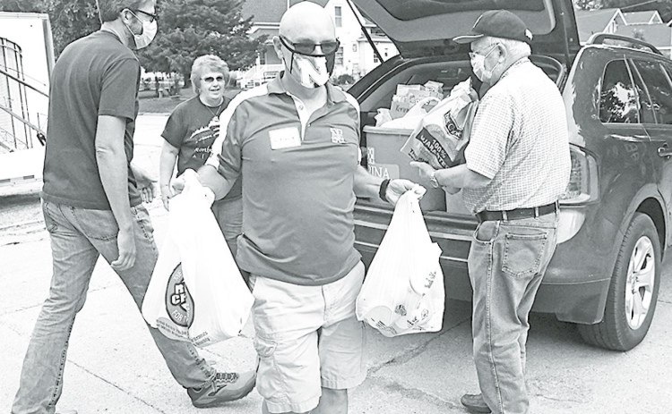 From left: John Christenson, Craig Shaffer and Chuck Anderson help unload bags and buckets filled with groceries during the Can Care-A-Van. News-Register/Jeni Moellenberndt