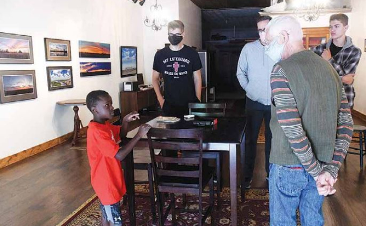 Featured artist Ernie Ochsner (front right) discusses his process with aspiring fellow artist, Jordan Ramaekers (front left) while his family members Preston, Ryan and Ethan Ramaekers listen in. (News-Register/Jeni Moellenberndt)