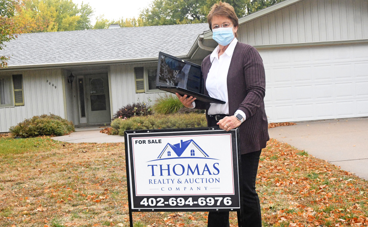 Laurie Pfeifer stands outside of one of the homes Thomas Realty & Auction has for sale. During the initial closures due to the pandemic, the local real estate firm utilized digital services to meet with clients and showcase houses.