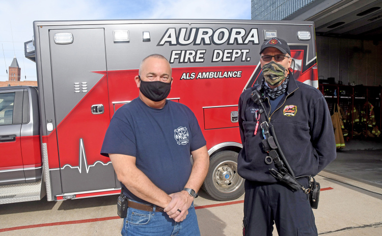 Aurora Fire Chief Tom Cox, left, and EMS Captain Brent Dethlefs stand by one of the city’s four ambulances, used as part of the new fire-based emergency medical service.