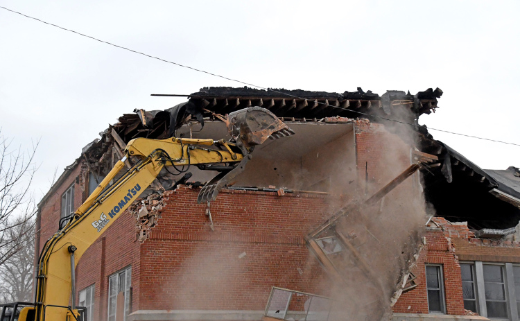The demolition crew forces out a window frame from the top floor as they slowly work to clear the sections nearest the event center.
