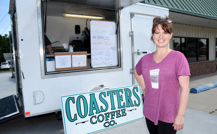 Sara Johnson stands by a trailer she is using as the temporary home of Coasters Coffee Co. Her business will move soon into the newly renovated space in the background, located at 1003 Q St., by the Aurora Wash House and Verizon.