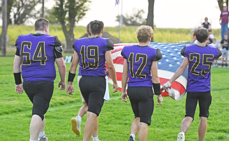 Fans on both sides of the field Friday in Hampton paused in silent tribute as senior Hawk football players carried an American flag across the field to be raised in honor of the 9/11 anniversary. Carrying the flag are from left: Michael McFarlane, Tyson Wolinski, Justin Gyhra and Austen Adams.