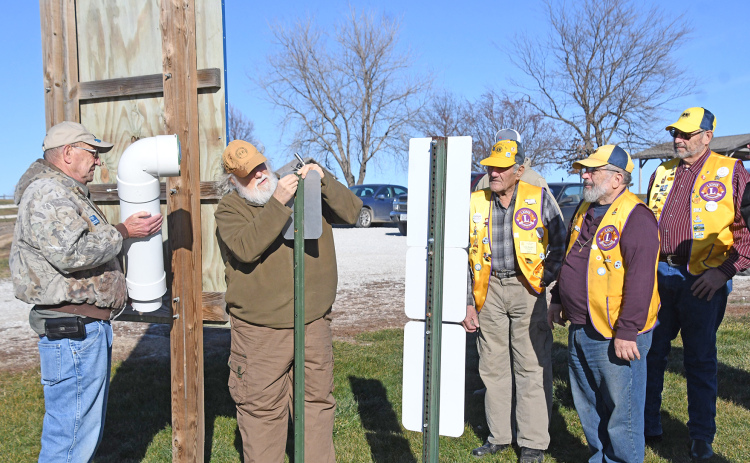 From left, Dick Berthold, Harold Fankhauser and members of the Aurora Lions Club work to install a fishing line recycling bin near the water’s edge at Pioneer Trails Lake northeast of Aurora.