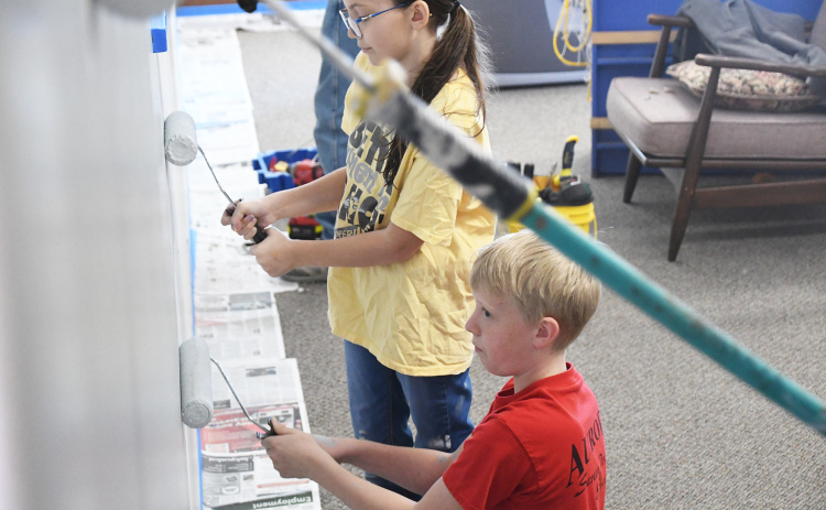Clarissa Orman and Wyatt Philippi help adults paint the wall of the Youth Center. Children have offered both help and insight into the center’s renovation.