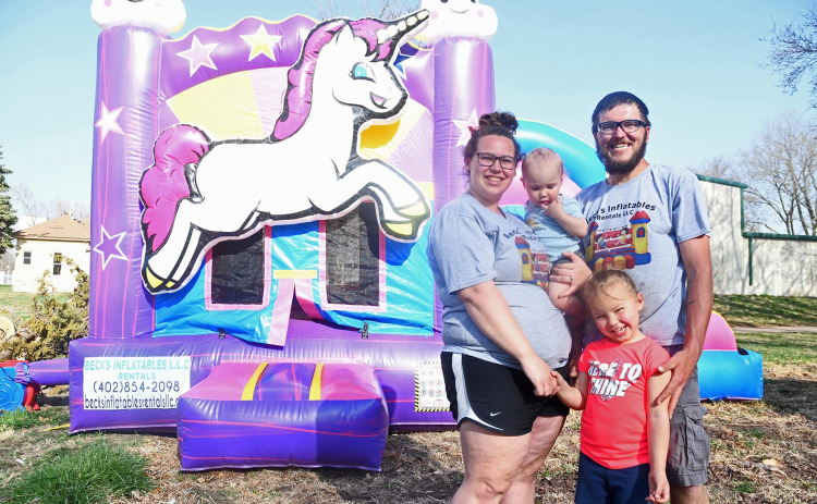 From left, Tessa, Hudson, Lyla and John Beck pose in front of the inflatable unicorn-themed bouncy house in their backyard. The family moved their business to Marquette after starting it in Kenesaw back in 2019.