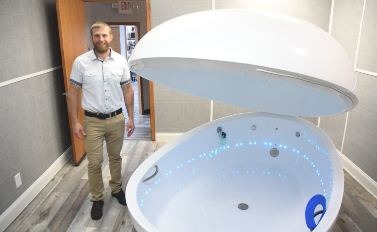 Jerry Lobeda, a 2009 Aurora graduate, stands next to his saltwater flotation device, a sensory depravation tank that is filled by water from an upstairs reservoir, drained and cleaned between each session at Sana Vida Wellness Center in Grand Island.