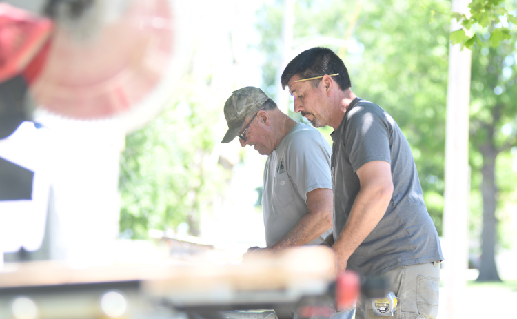 Ryan (right) and Eugene Bamesberger work on a piece of wood that will soon be sawed into measured  into planks. Materials like wood, concrete, latex, paint, windows and doors consistently are delayed for often months at a time.