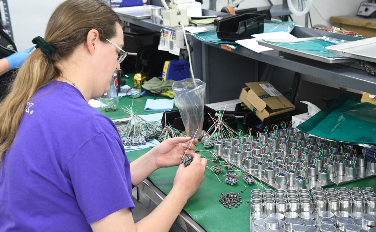 Taylor Lemburg prepares a circuit board assembly for encapsulation at International Sensor System’s plant in the Aurora Industrial Park. Getting parts on time, consistently, has become a supply chain challenge for ISSI and other local manufacturing companies.