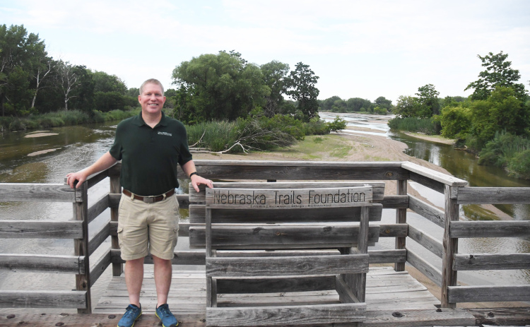 President of the Nebraska Trails Foundation and Dark Island Trails board member Jason Buss pauses for a photo on the mile-long bridge over the Platte River near an island between the banks.