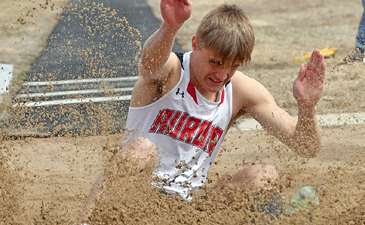 Aurora senior Carsen Staehr crashes into the sand pit during his final run through the long jump event, winning by half an inch over second place at Friday’s home invite.