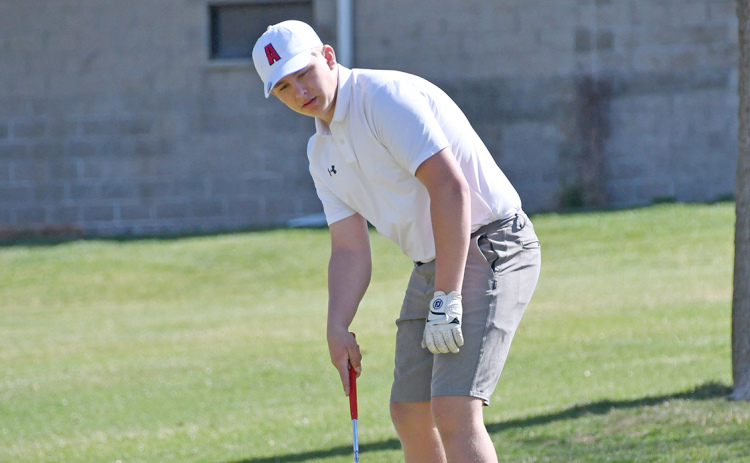 Luke Grosshans watches his putt on the par-3 4th hole trickle back down toward the hole as the wind whips the flag around on the ground at the York Invite Thursday. Grosshans carded an 80 for his first varsity medal.