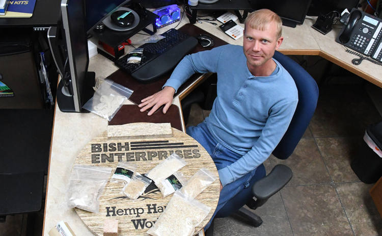 Andrew Bish, COO of Bish Enterprises and CEO of Hemp Harvest Works, shows in his Giltner office some of the products that can be made with hemp on top of a sign made of hemp wood. Blocks, absorbant, feed and other uses for hemp could foster growth of the farming market in the future, stated Bish.