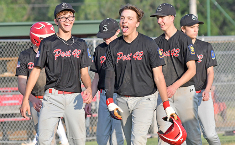 Jace Dorsey (middle) and his teammates celebrate after erasing a 9-0 deficit to defeat Twin River 12-11 at Mitchell Field June 7.