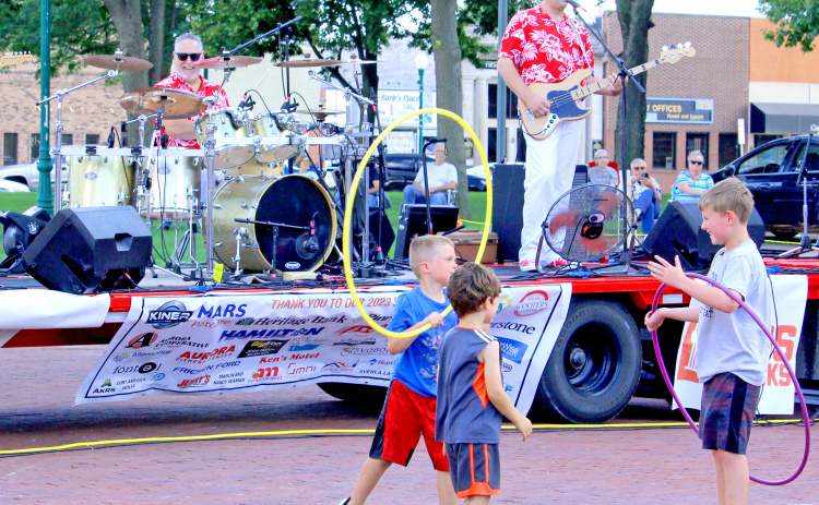 A group of boys make creative play using the hula hoops on the street in front of the bandstand at Friday’s opening night of Bands on the Bricks on the Aurora town square. Ricky Lee and the Fabulous 50s opened the 2023 season of the popular summer festival.