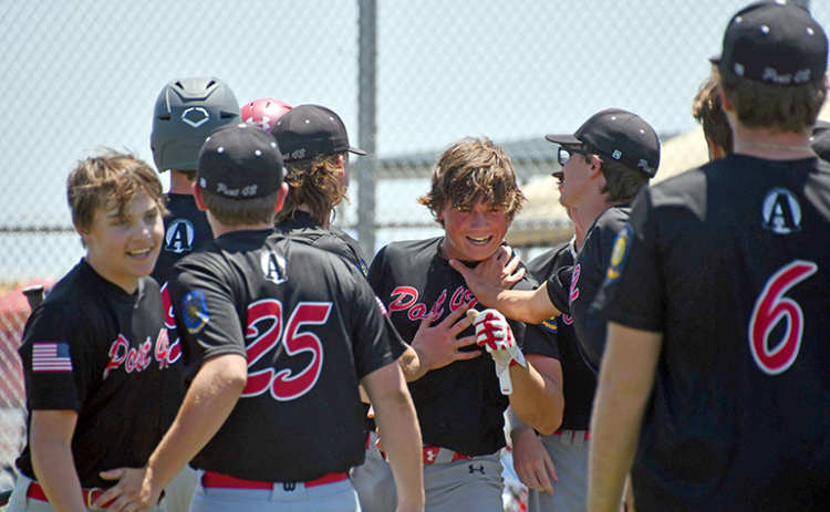 Collin Stolpe touches helmets with coach Jarrett Havens, pictured right, before being mobbed by his teammates at the plate after his third inning home run in a 20-14 loss to York Monday in the B-1 area tournament.