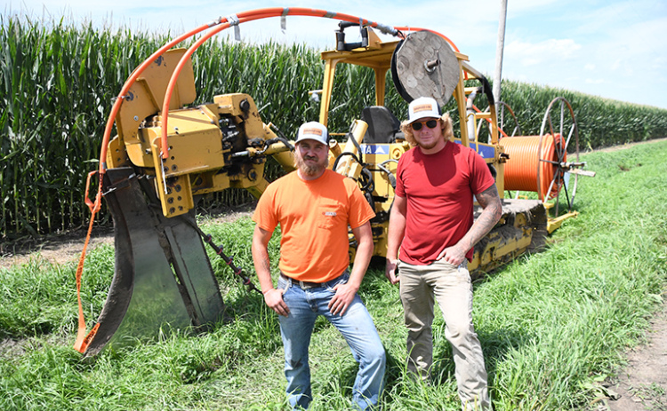 Noah Tripp, left, and Jared Snyder stand near drilling equipment as partners in their new Quality Underground LLC business.