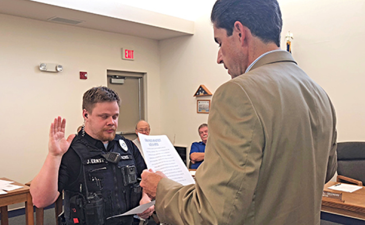 Joseph Ernst, left, is sworn in as a new Aurora police officer by City Attorney Ross Luzum.