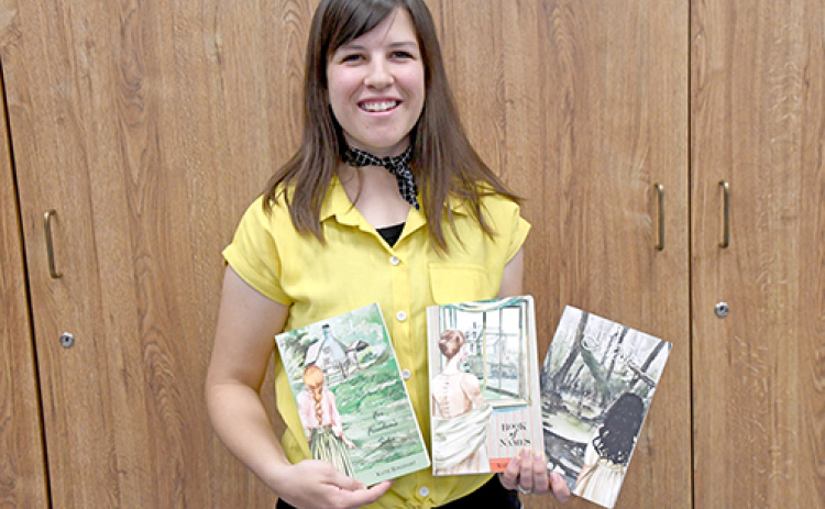 Author Katie Roszhart proudly holds three of her books from her book series, Naioth Adventures.