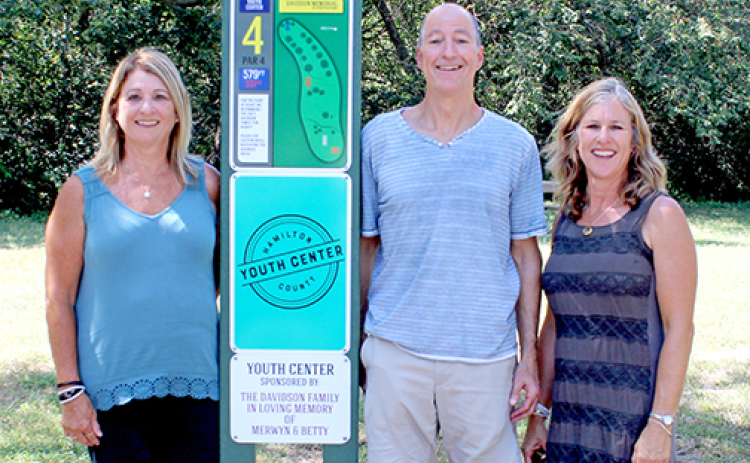 Lila Wolf of Aurora and her siblings, Mark Davidson of Lawrence, Kan. and Sharon Harthoorn of Norfolk stand at the tee pad for Youth Center hole of the Merwyn and Betty Davidson Memorial Disc Golf Fitness Trail on Sunday afternoon. The newly completed course in Streeter Park is named after their parents.