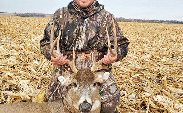 Jon Bruner poses in a cornfield with a large buck he took with a rifle last season near Alvo.