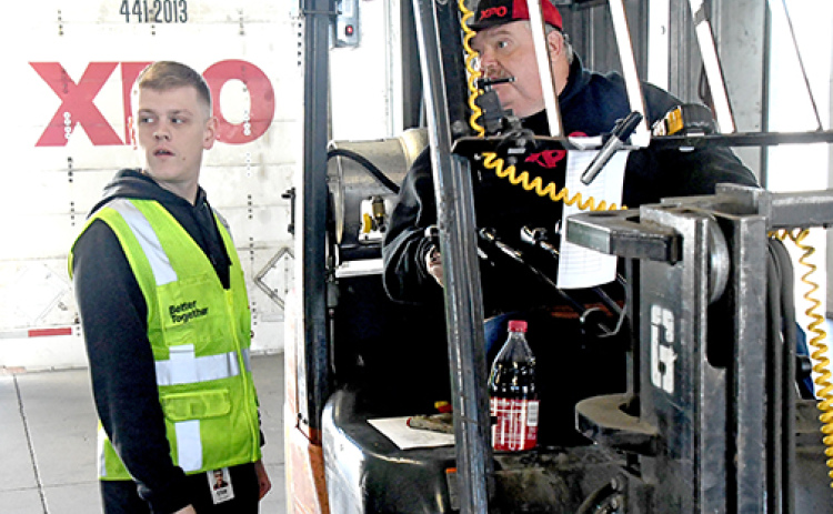 Erik Holloway, pictured at left, utilizes some of the logistics training he received in the US Army in his new job as a freight operations supervisor at XPO in Aurora.