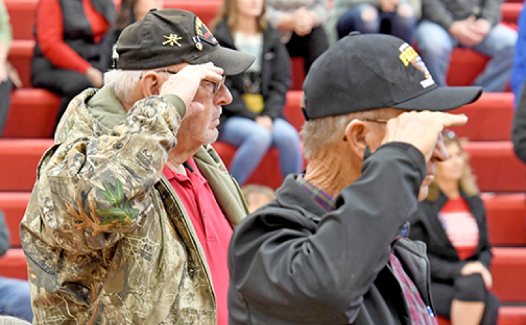 U.S. Army veterans salute as the  Army Song is played by the Aurora High School Band at Friday’s Veterans Day program at the high school.