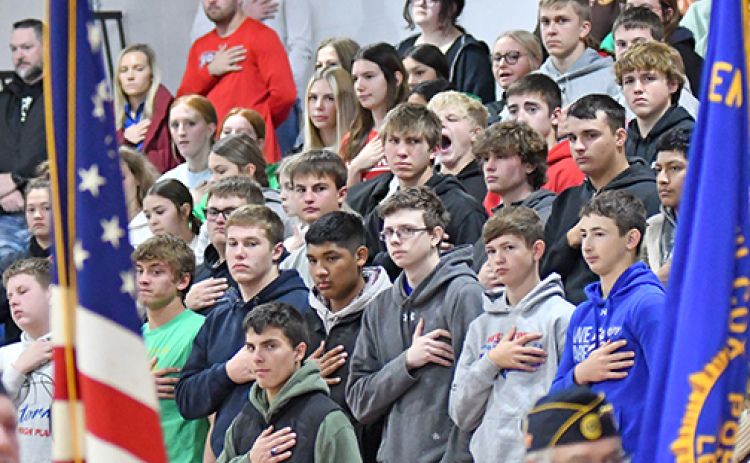 Students at High Plains Community Schools stand at attention as members of the American Legion post the colors.