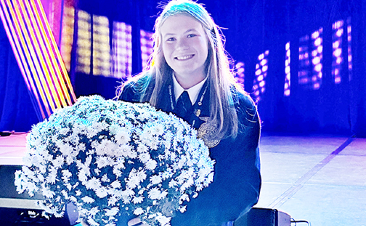 Morgan Bonifas holds a pot of her mums near the stage at the national FFA Convention in Indianapolis earlier this month, where she was recognized as one of the four national finalists in FFA proficiency in the area of specialty crop production and entrepreneurship.