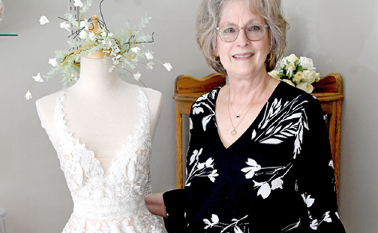 Dream Designs Bridal Shop owner Deanna Powell stands next to one of the nearly 800 dresses in her shop. She recently learned that the building her shop has occupied for over 20 years was built by a seamstress at the turn of the 20th Century.