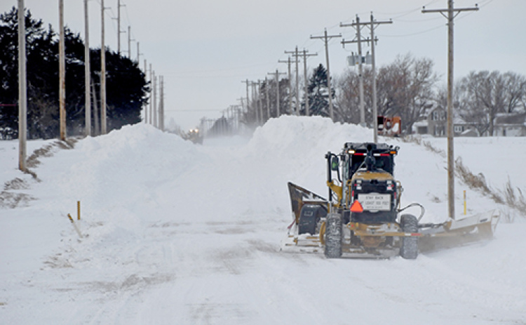 Two motor graders equipped with v-plows continue to work Monday afternoon to open up a two-mile stretch of 12 Road just west of Aurora. The process had started at 7 a.m. and by 1:30 p.m. only a one lane track had been cleared.