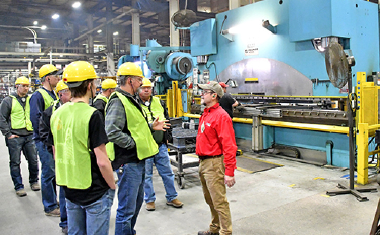 Tour guide Tom Ernstmeyer, right, answers a question from one of the members of his tour group as it pauses before a 700 ton press on the floor of the Case IH factory in Grand Island.