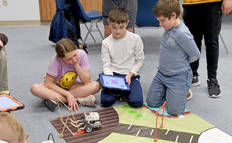 One of the many challenges students at Hamilton County 4-H faced at Lego Robotics was to put in the right measurements to steer their robots around obstacles. From left, Lillie Land, Cody Paton and Dalton Land watch as their robot attempts to navigate through the course.