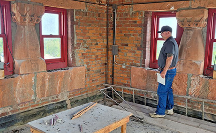 In the uppermost floor of the Hamilton County Courthouse tower custodian John Bish holds his hand over the photoelectric switch to light up the beacons mounted in each middle window.