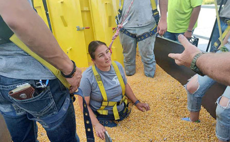 EMT captain Erin Ditloff goes waist deep in the training trailer to help firefighters train for a grain rescue scenario. Coffer dams were used to prevent grain from falling back as firefighters dig Ditloff and a training dummy out throughout the evening.